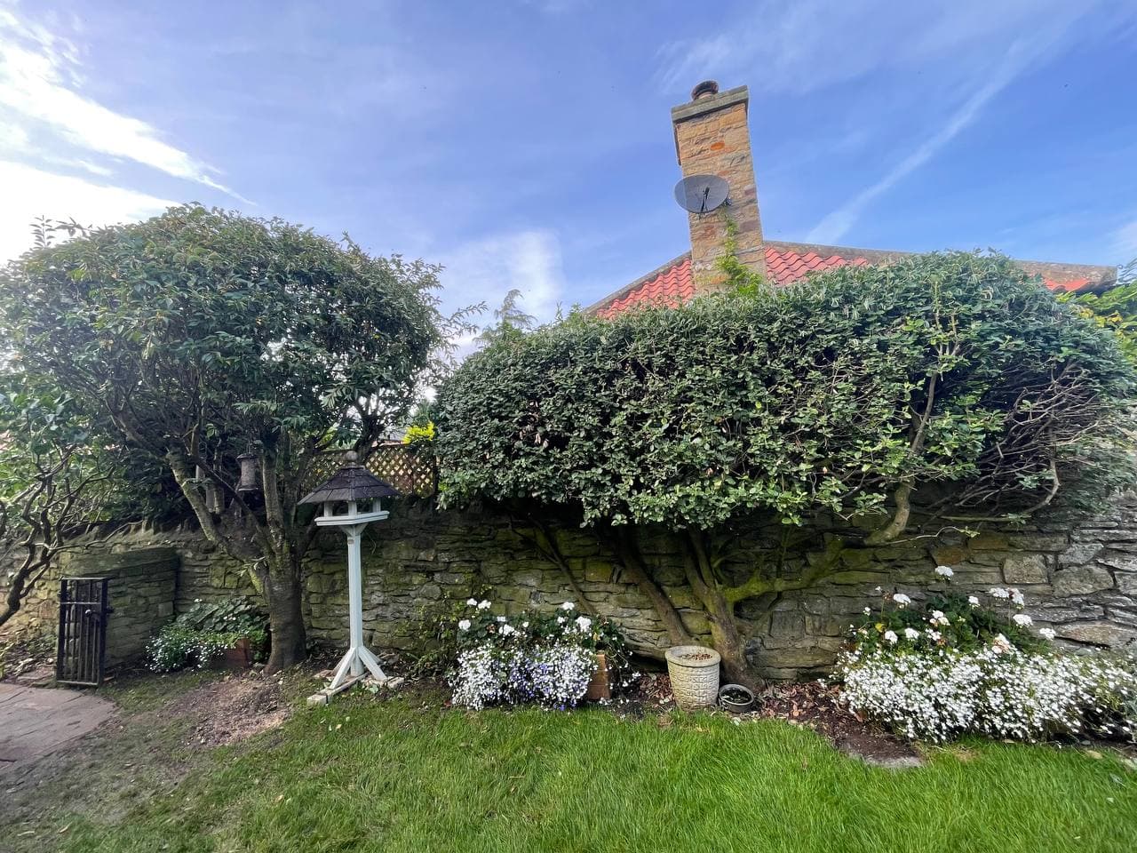Shaped topiary and small trees kept neat above a stone garden wall